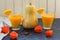 Two glasses of pumpkin juice and a pumpkin on a table decorated with physalis flowers. A concept of useful seasonal smoothies.