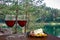 Two glasses of red wine with charcuterie assortment against view of small pine trees near turquoise lake