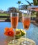 Two glasses of rose bubbles champagne or cava wine served outside on paradise island with palms and green grass