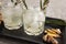 two glasses with a soft drink, homemade lemonade with ginger. close angle. gray background.