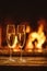 Two glasses of sparkling champagne in front of warm fireplace. C