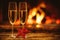 Two glasses of sparkling champagne in front of warm fireplace. C