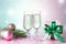 Two glasses of sparkling wine, gift box with bow, decorations. Composition in pink and green for Christmas, New Year. Still life