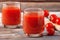 Two glasses of tomato juice on a wooden table, on a wood background, fresh drink