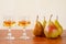 Two glasses of traditional bulgarian home made fruit brandy krushova rakia and four pears on a wooden table against light beige