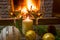 Two glasses of white wine, candle, christmas glass balls, near cozy firepace