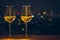 Two glasses of white wine on wooden table of rooftop bar with colorful love shape bokeh of city light and space for text