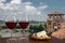 Two glasses of wine with charcuterie assortment on view of Verona, Italy. Glass of red wine with different snacks - plate with ham