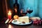 Two glasses of wine, a plate with cheese, a candle as a Mediterranean scene in front of a blue vintage wall. Generative AI