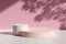 Two glossy pastel pink and cream colored round podiums against pink wall with tree leaf shadows and natural sunlight
