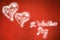 Two glowing hearts on red metalic sheet Valentine`s Day background.