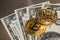 Two gold coins bitcoin lie on hundred dollar bills, photo close-up