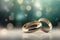 Two gold wedding rings are in front of a bokeh background, in the style of digitally enhanced, light green