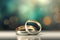 Two gold wedding rings are in front of a bokeh background, in the style of digitally enhanced, light green