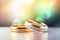 Two gold wedding rings are in front of a pastel bokeh background, in the style of digitally enhanced,