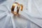 Two gold wedding rings on white decorative cloth background