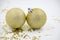 Two golden christmas balls baubles on a white background with blurry golden stars