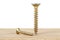 Two golden screws on wooden plank, white background