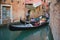 Two gondolas diverge in a narrow urban canal. Venice