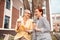 Two good-looking elegant colleagues sitting outdoors while laughing