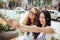 Two good looking thin girls with long dark hair,dressed in casual stye,sit at the bench and take a selfie,