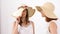 Two gorgeous girls in large summer hats over a white wall in studio