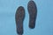 Two gray insoles for shoes on a blue background