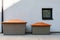 Two gray plastic boxes with an orange lid for storing sand, salt for janitorial work and communal service, stand against a gray