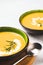 Two green bowls with thick butternut squash bisque garnished with heavy cream and rosemary on gray concrete table