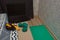 Two green dumbbells, a black skipping rope and a laptop on the edge of the bed, next to a sports mat on the floor. Sports at home