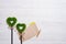 Two green grassy hearts, sheet of paper and pencil on a white wooden background