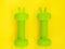 two green heavy dumbbells with leaves in shape of Easter bunny on yellow background. Easter fitness and training