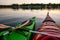 Two green and red wet kayaks float still together on water surface with two crossed orange paddles, summer evening, sea kayaking