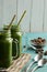 Two green smoothies of kale and spinach in mason jar mugs with s