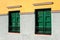 Two green windows with shutters on multicolored wall. Canary Ten