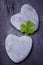 Two grey heart shaped rocks with leafed clover on a tile