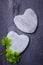 Two grey heart shaped rocks with some shamrocks on a tile background