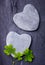 Two grey heart shaped rocks with three lucky clovers on a tile