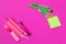 Two groups of pink and bright green office equipment are lying on opposite sides on pink surface isolated