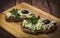 Two guacamole sandwiches on a Board and wooden background decorated with olive and parsley