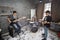 Two guitarists and drummer play in room