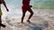 Two guys carry a water ball. Kid jumping in the waves. Sea vacation for family with kids.