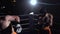 Two guys in helmets and boxing gloves to fight in the ring in the dark . Slow motion