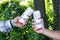 Two guys are holding cans of Budweiser Lager Alcohol beer in nature.