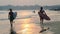 Two guys a surfer walking on the beach at sunset