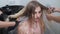 Two hairdressers comb woman long wet blonde hair after dyeing procedure