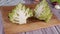 Two half of Roman Romanesque cabbage Romanesco on a wooden cutting board next to other vegetables.