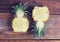 Two halves of juicy pineapple on old wooden table