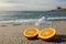 Two halves of orange on the sand and a juicer.