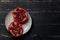 Two halves of pomegranate fruit on plate on black wooden background.